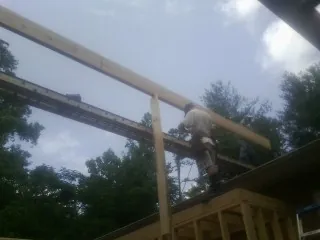 Carpenter setting a ridge beam over a new addition frame — Ice Dam Removal by Roofing Brothers in Salemburg