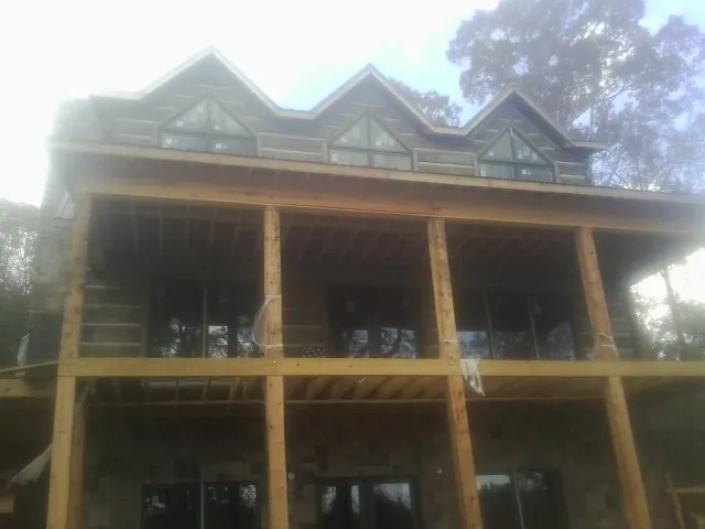 Dormers and porch framing on a large log home under construction — Roof Coating work by our crew in Salemburg