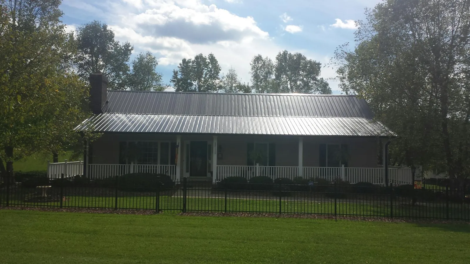 Gray metal roof on a brick ranch with a full width front porch — Gutter Guard Installation work by our crew in Salemburg