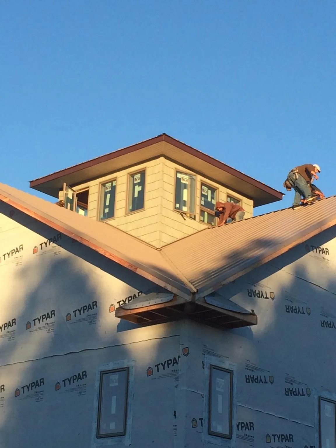 Roofers working around a rooftop cupola on a new metal roof at sunset — Roof Waterproofing in Salemburg by Roofing Brothers